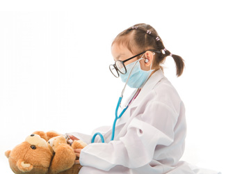 Un niño vestido de médico inspecciona un oso de peluche