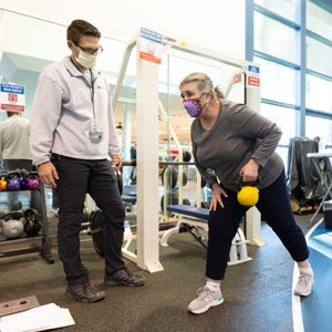 A personal trainer helps a client work out.