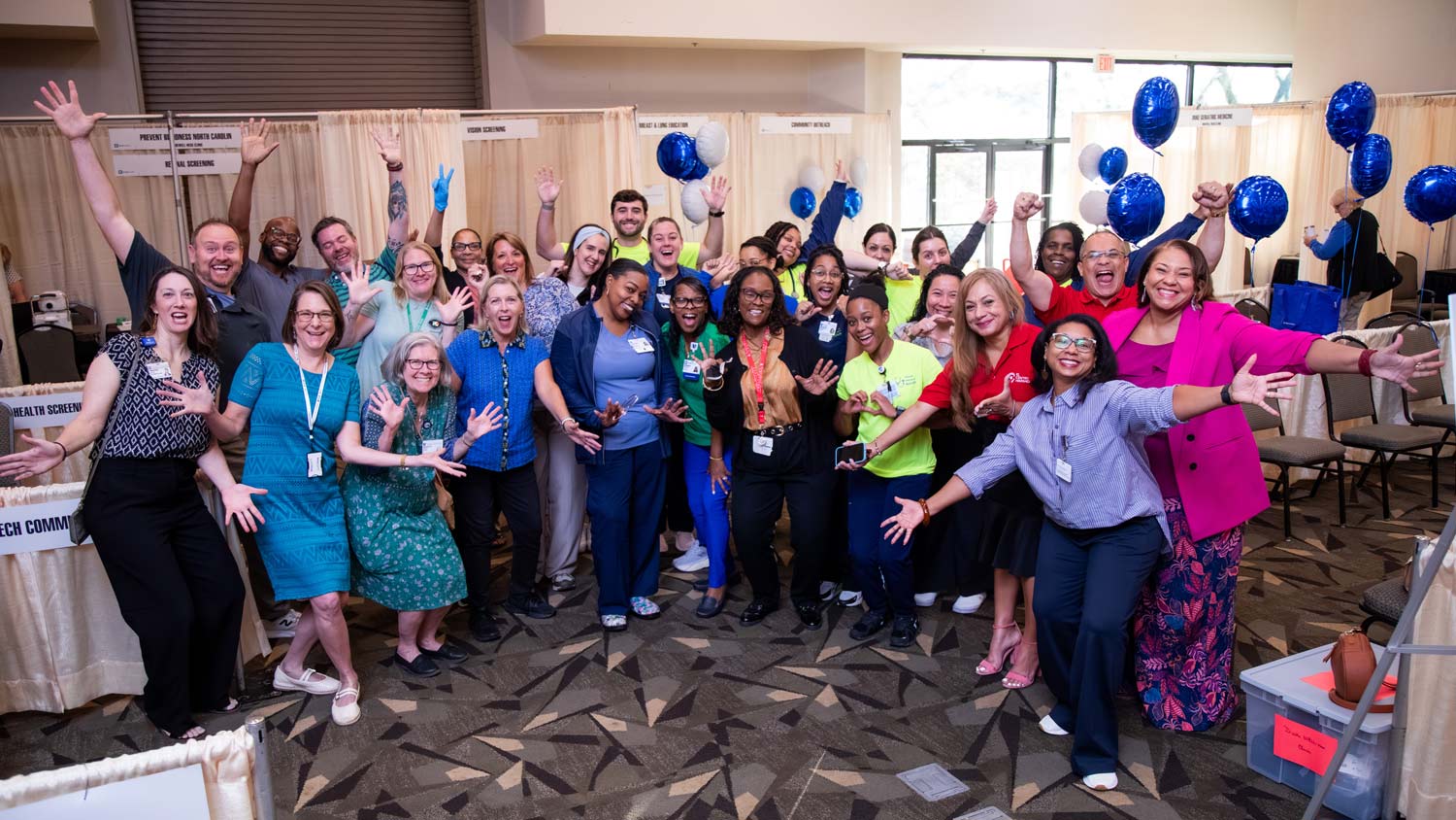 A group of vendors smiles and hold their arms open in celebration