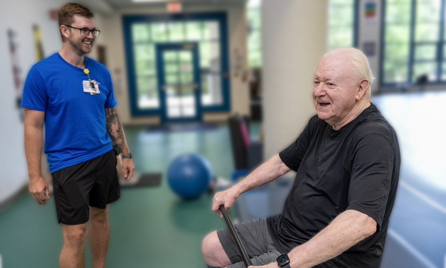 A trainer watches a client lift a bar