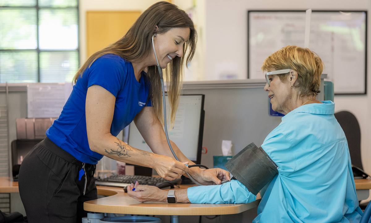 A provider takes a clients blood pressure at a desk