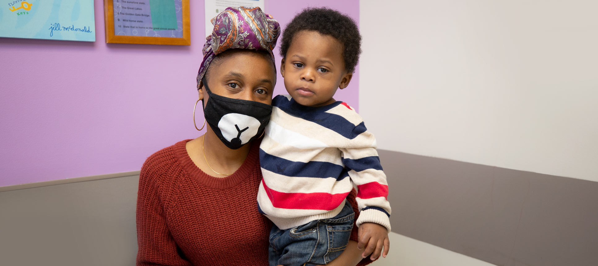 A mother and her young male child pose in a clinic room