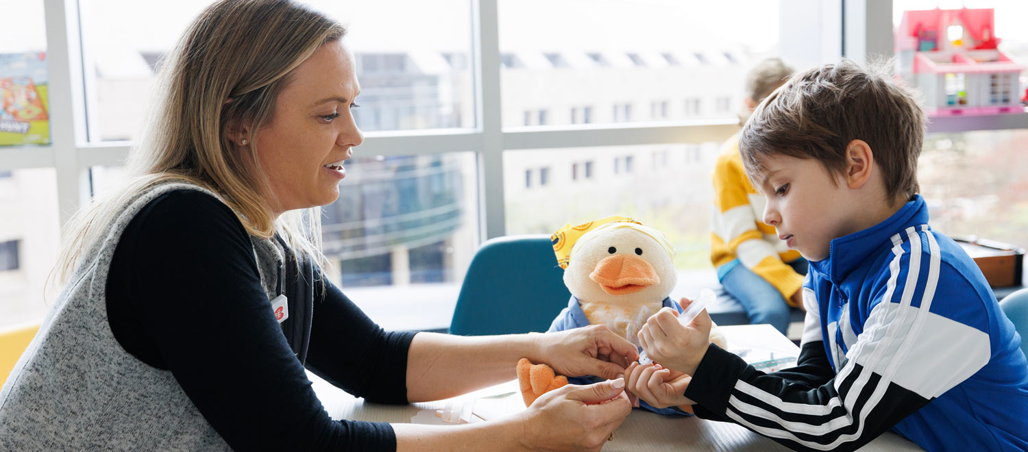 A therapist shows play medical syringes to a child