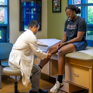 Un médico examina la rodilla de una paciente.