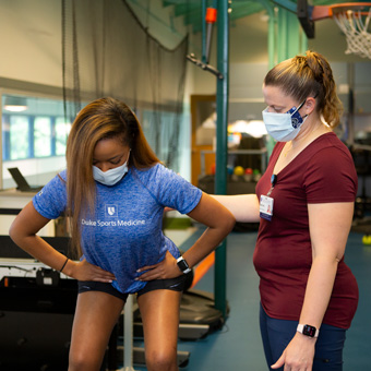 A provider helps a patient do a squat