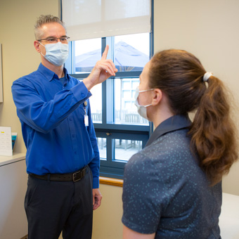 A provider holds up a finger for a patient to follow with their eyes during a concussion test