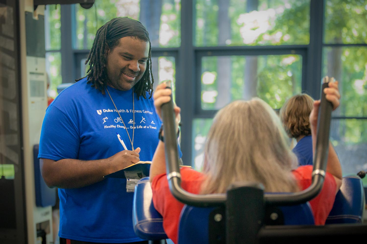 A trainer works with a client on a weight machine