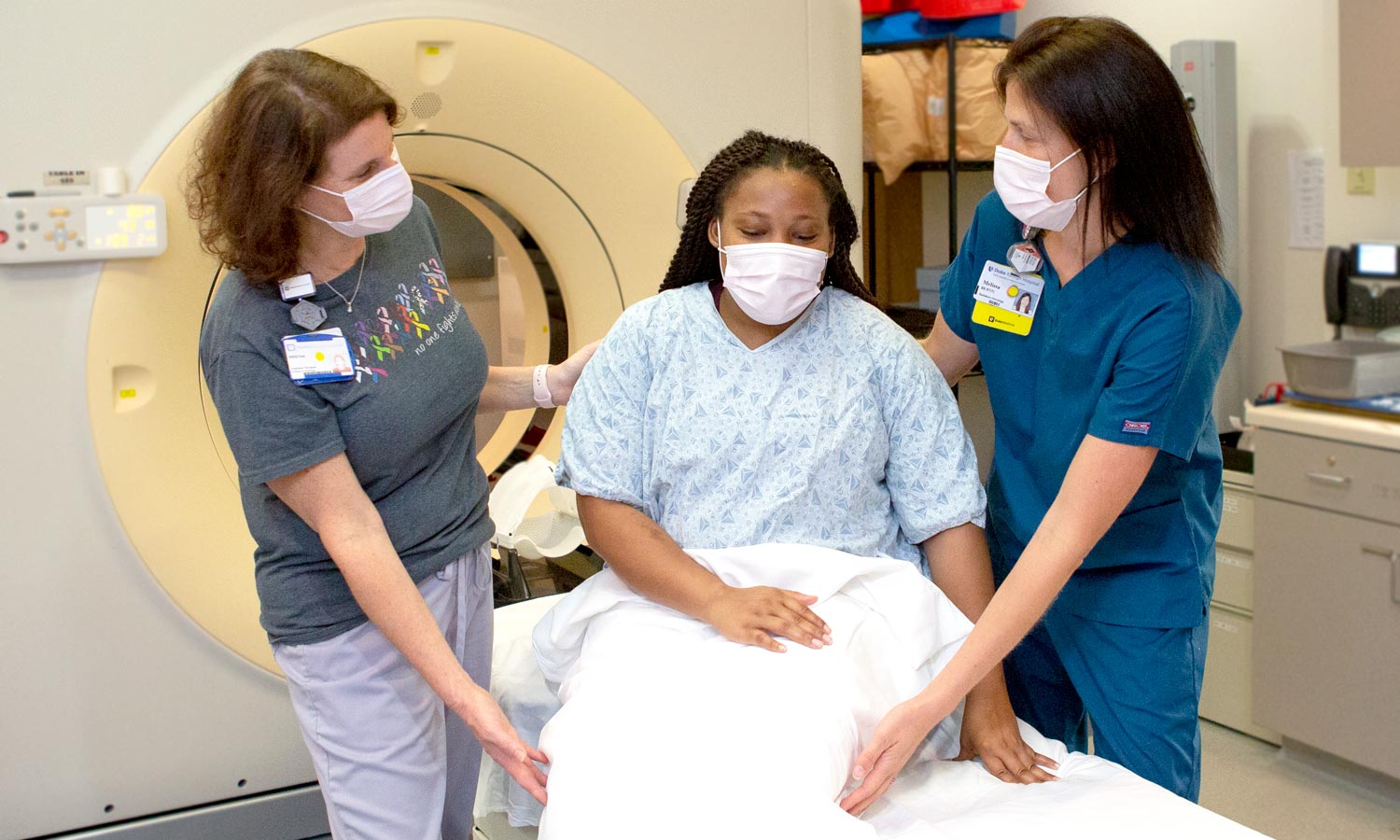Two providers help a patient get ready for treatment