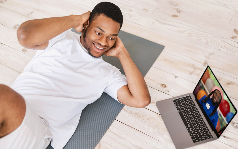 A man works out with a personal fitness trainer on his computer