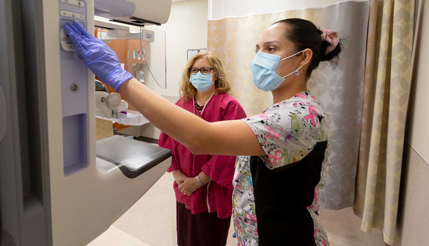 A provider helps a patient prepare for a mammogram