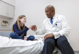A doctor fist bumps with a pediatric patient 