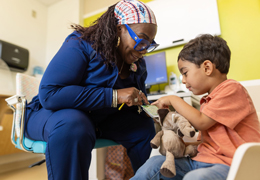 A nurse and a pediatric patient look at her badge together