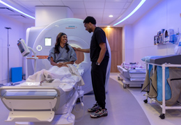 A provider helps a patient get on an MRI machine