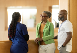 A nurse speaks with a couple in a lobby