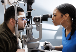 A provider looks at a patient's eyes through a slit lamp