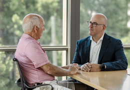 A doctor speaks with a patient in a consult room