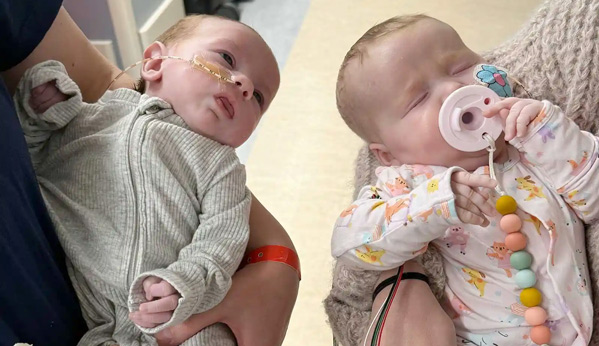 Two babies are held by their moms