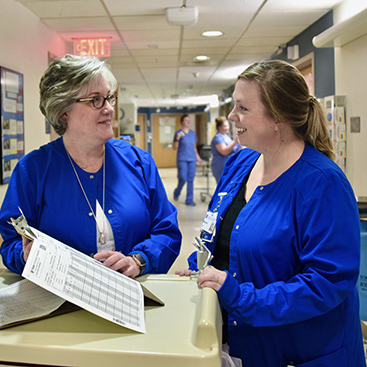Two providers look at a chart together in the hall