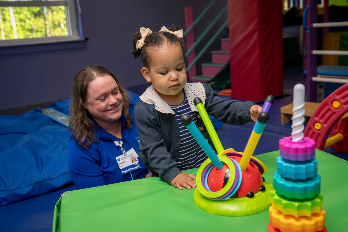 Therapist works with a child on reaching in standing