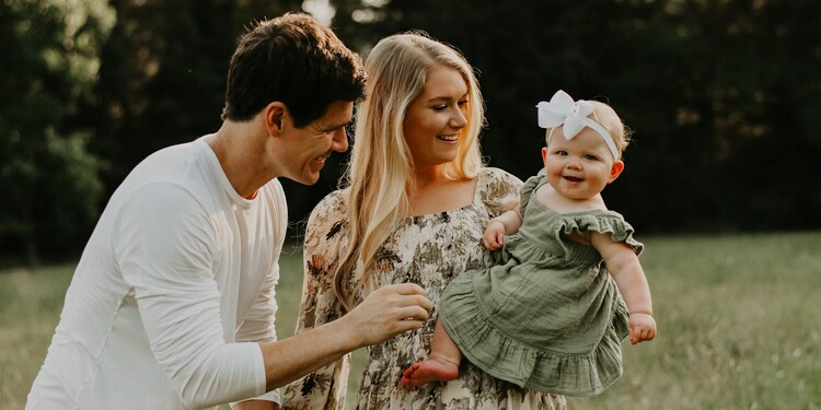 Marcie O’Neill and her husband smile as they look at their young daughter 