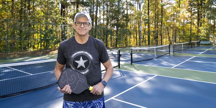 Ralph Peeler holds his pickleball racket on a court