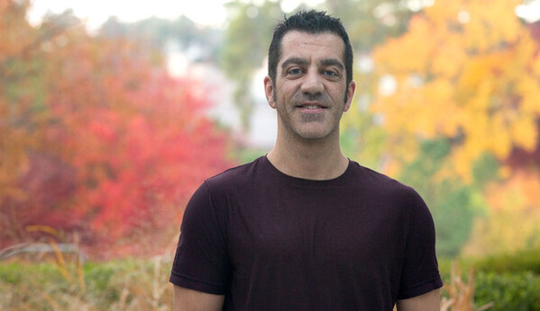 Dan Kummer stands outside in front of fall colors
