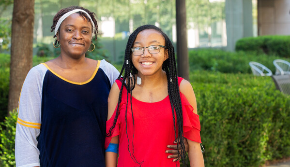 Mother and daughter, Teyanna and Tyra Ingram smile together outside. 