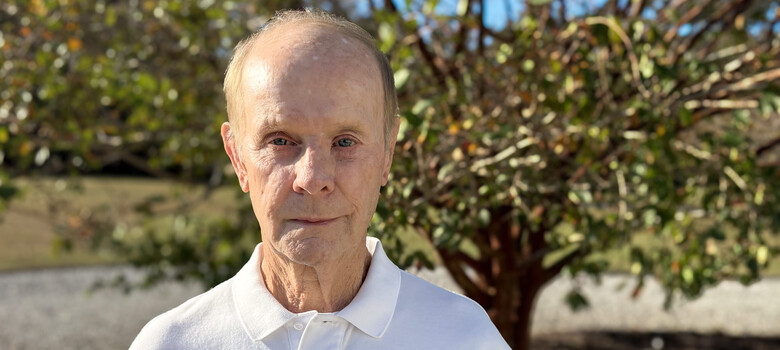 Charles stands outside in front of a tree