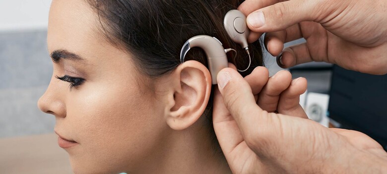 A provider helps place a cochlear implant onto a patient's ear