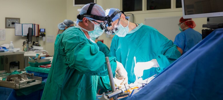 Michael Lidsky, MD, and Justin Barr, MD, work to implant an HAI device into a patient's abdominal wall. 
