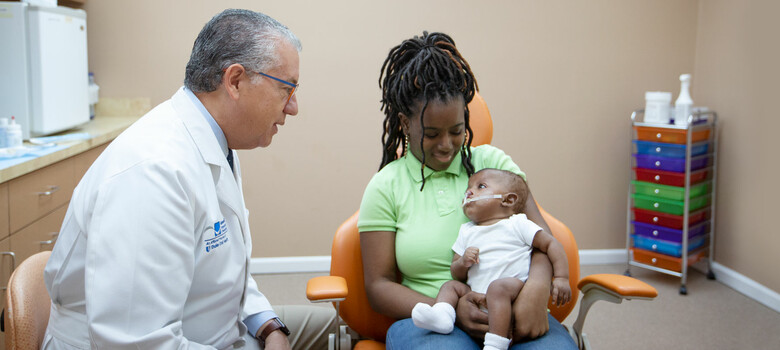 Pedro Santiago meets with a mother and her child, who is receiving treatment with the NAM device.