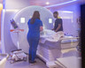 Two technicians help a patient get into an MRI machine