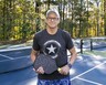 Ralph Peeler holds his pickleball racket on a court