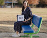 Kathryn Mathews sits on a bench and holds a photo of her mother