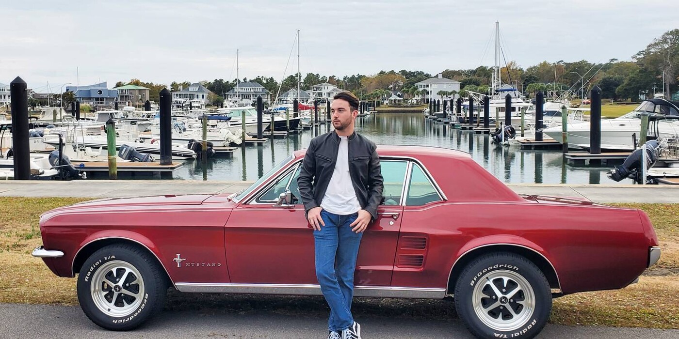 Harvey Squires stands in front of his 1967 Mustang at a marina.