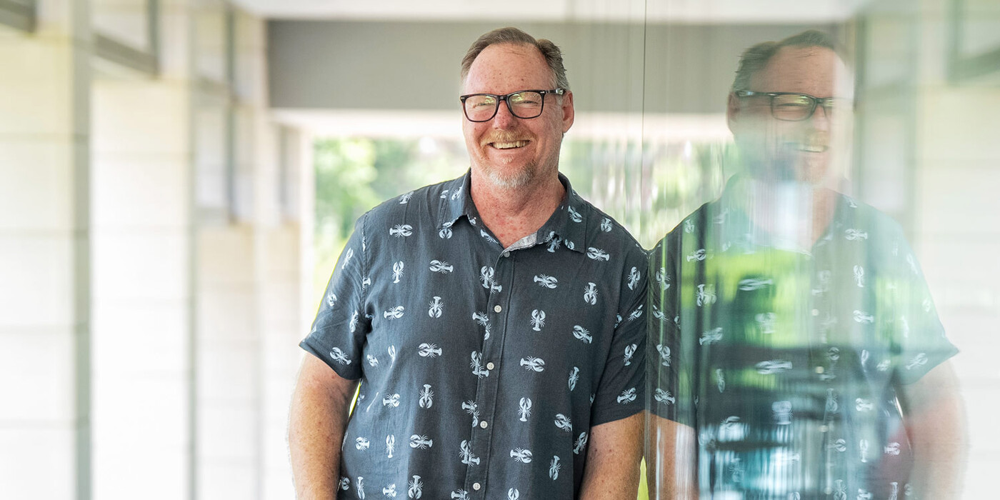 Brad Dugai leans against the glass wall of a building