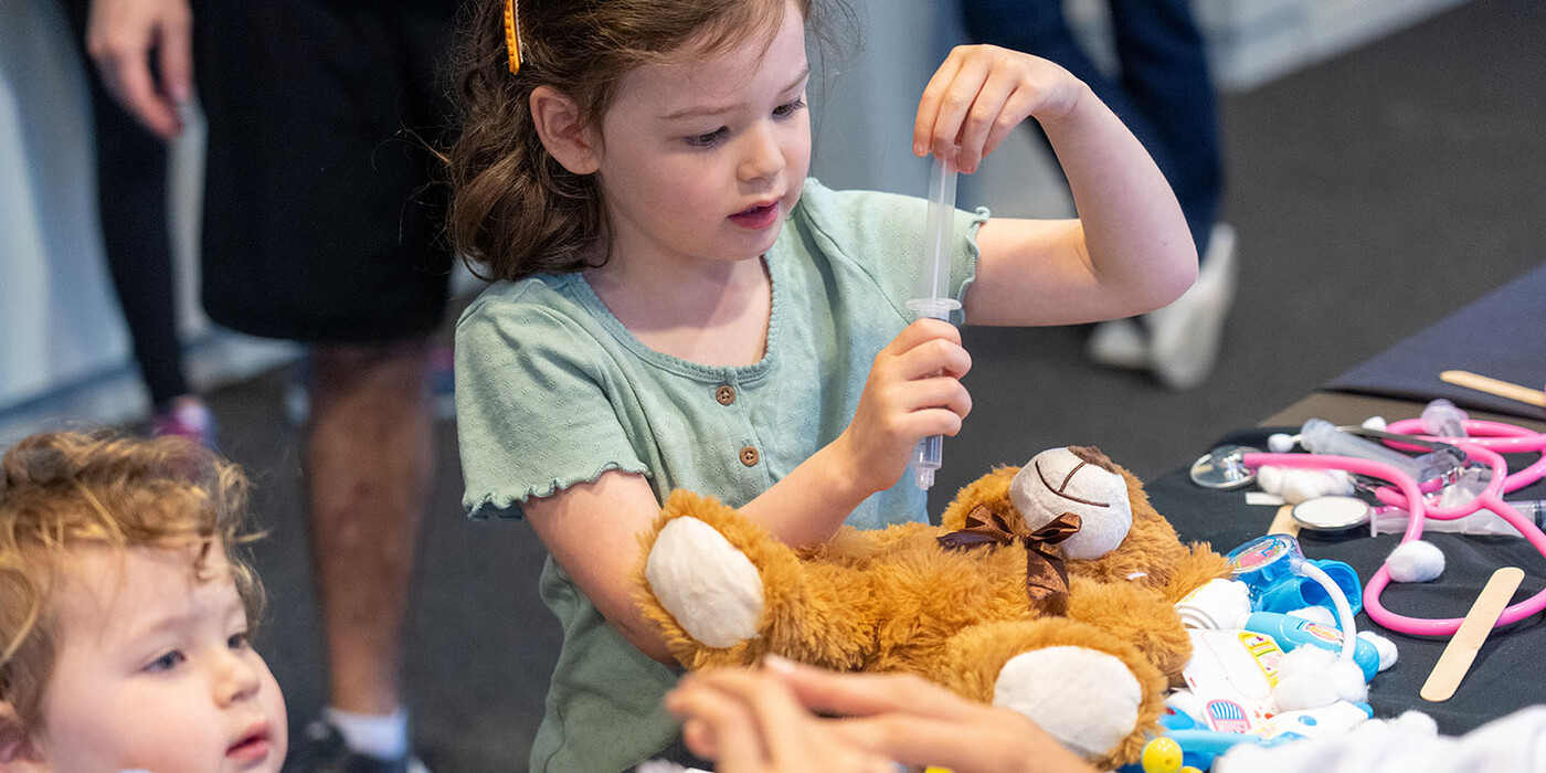 young child performing a physical with her teddy bear on the table
