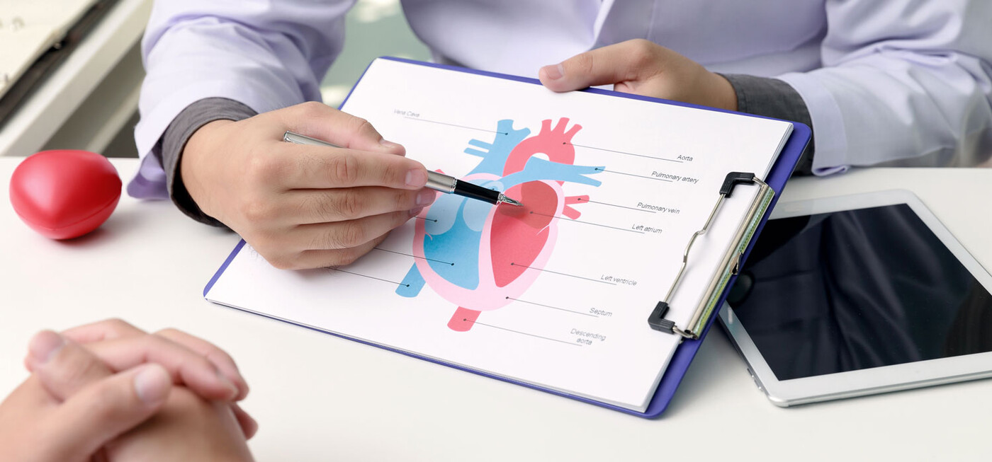 A doctor points to a diagram with a heart