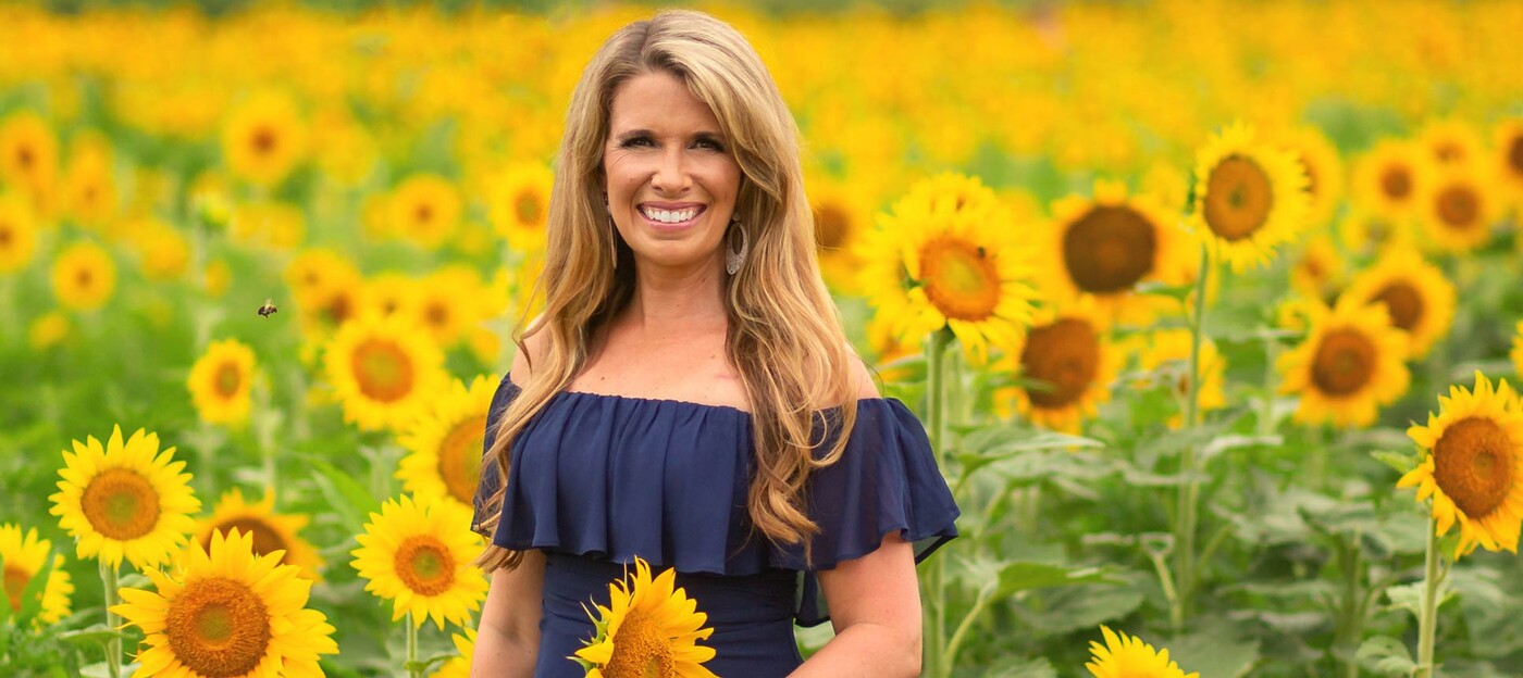 Susan VanNess stands in a field of sunflowers 