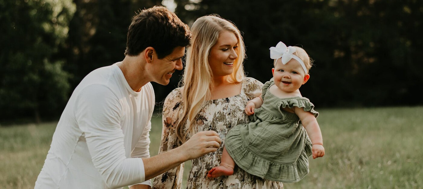 Marcie O’Neill and her husband smile as they look at their young daughter 