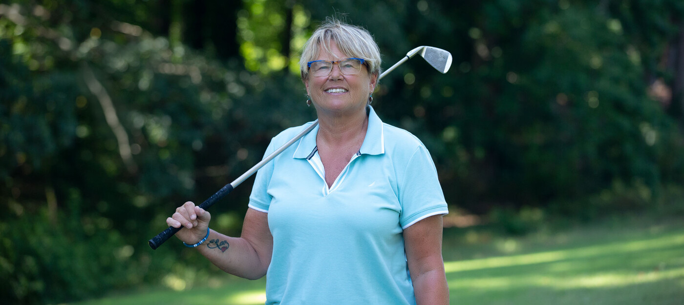 Denise Schroeder poses on a golf course with her club over her shoulder