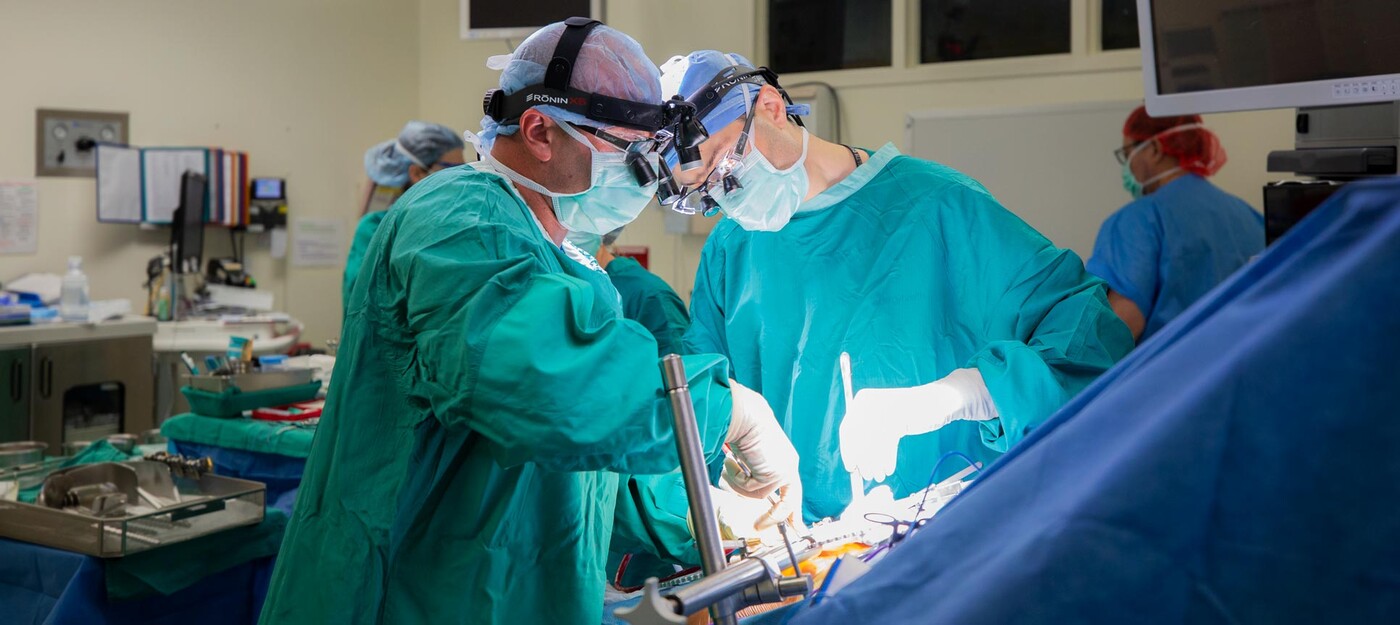 Michael Lidsky, MD, and Justin Barr, MD, work to implant an HAI pump into a patient's abdominal wall. 