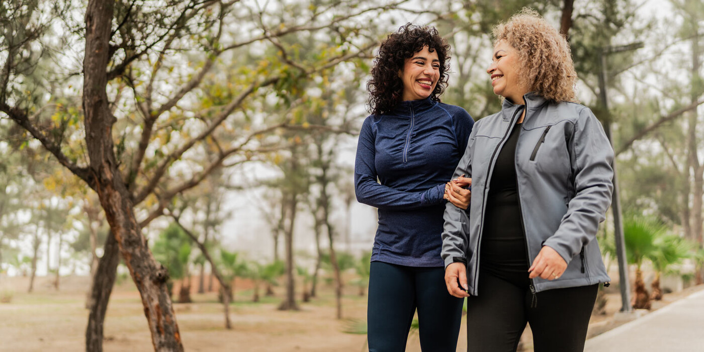 A mother and daughter walk arm in arm on a path