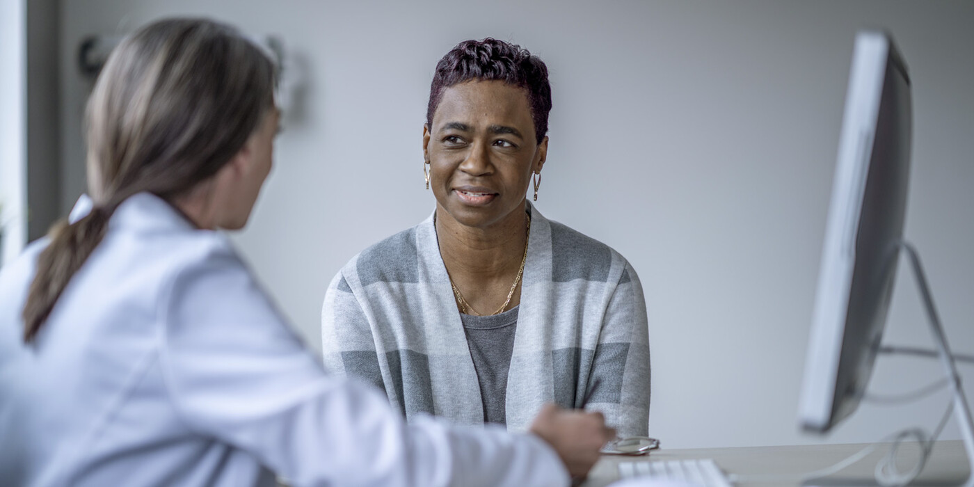 A woman talks to a doctor who is taking notes