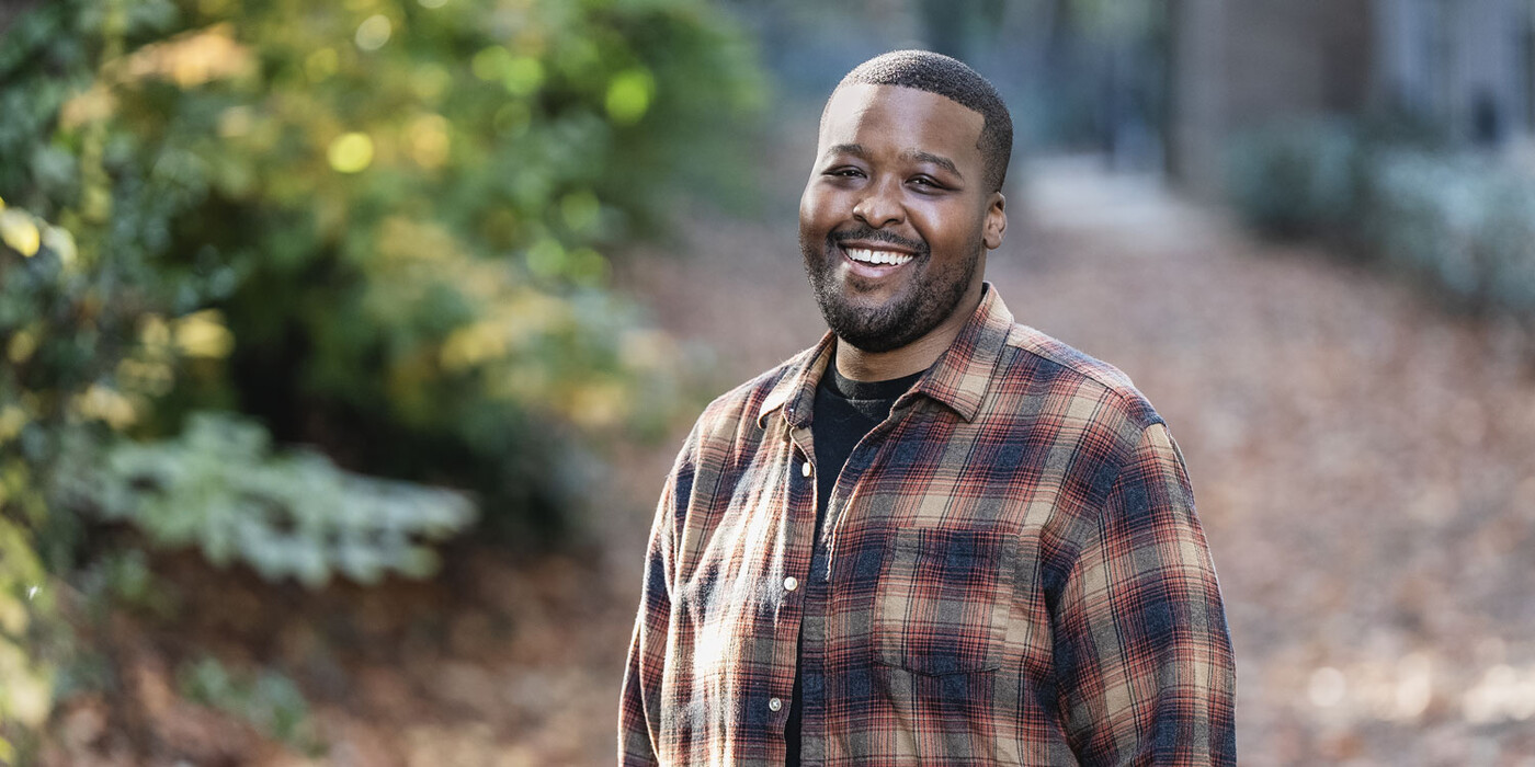 Bryant Grey smiles outside in front of some foliage 