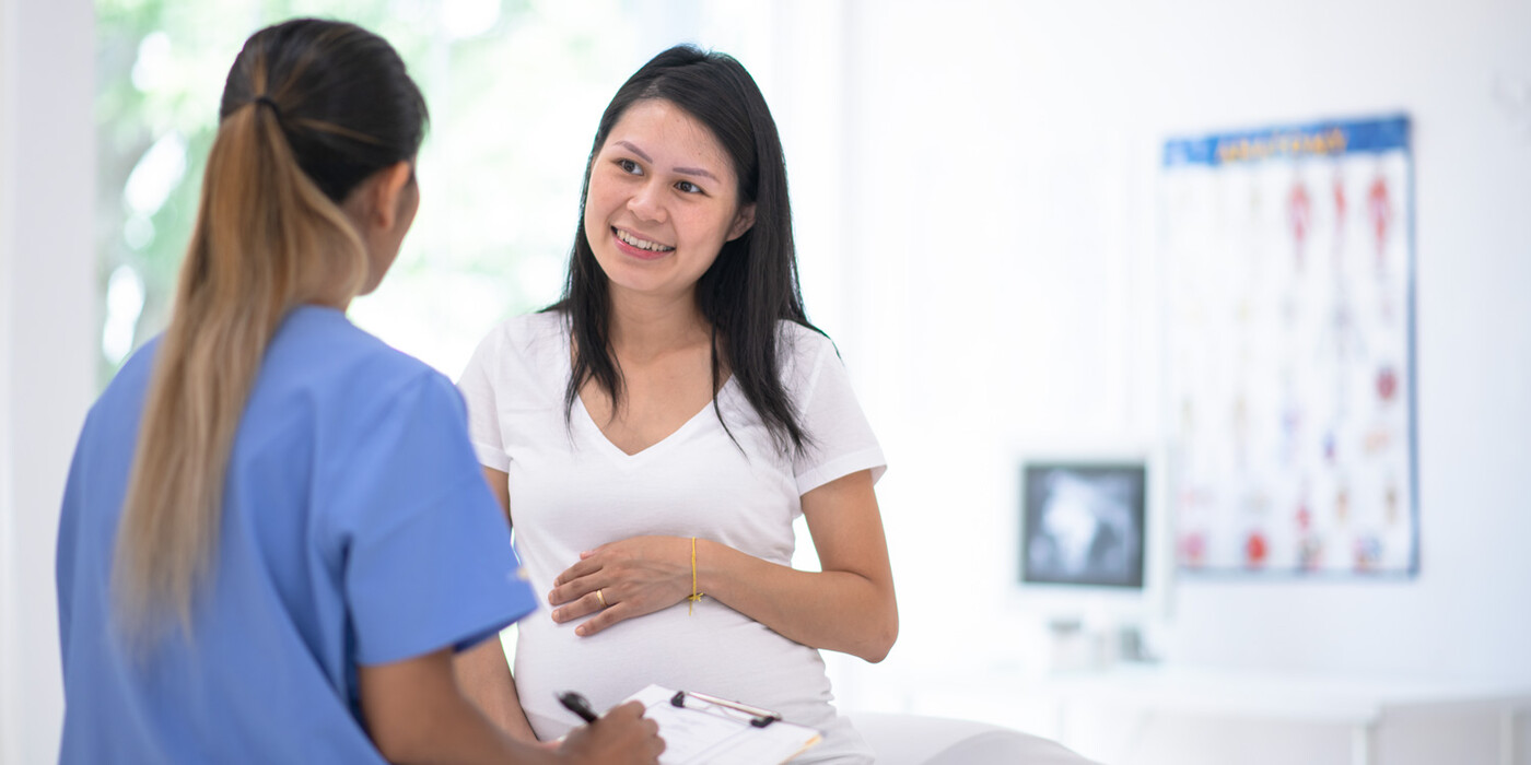 A nurse fills out a form with a pregnant patient