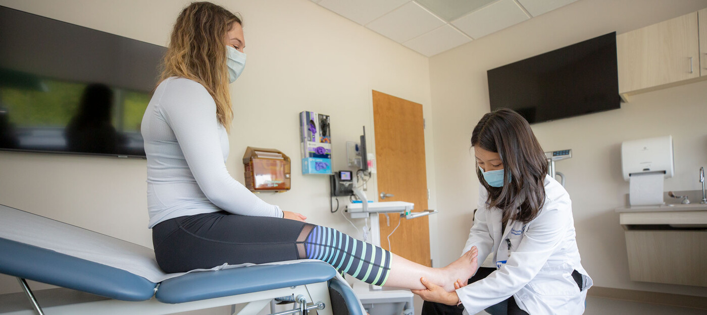 A medical provider looks at a female patient's ankle and foot