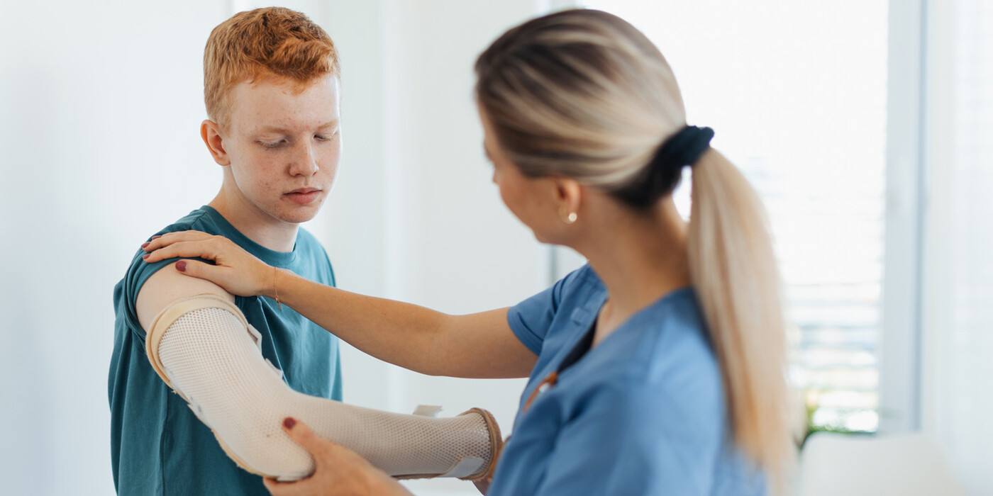 A medical provider examines a teenager's elbow brace