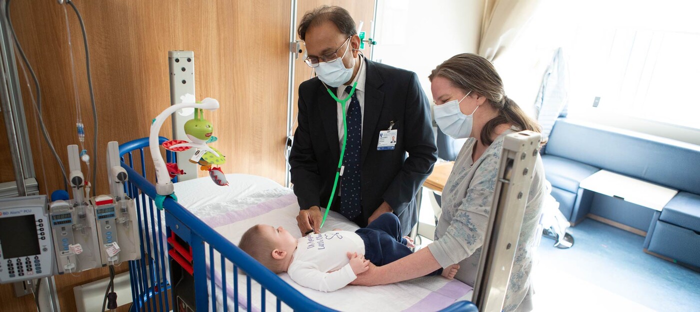 Dr. Prasad listens to a baby's chest as the child's mother watches