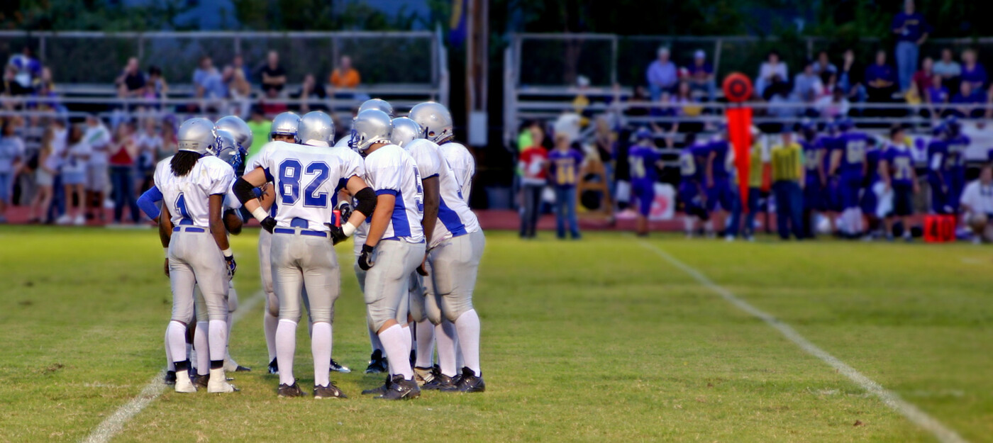 A football team huddles on the field